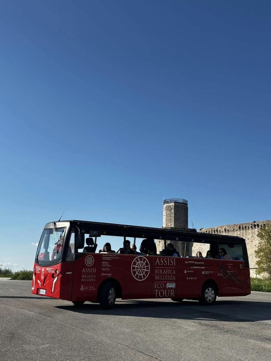 červený autobus jedoucí po ulici s lidmi uvnitř