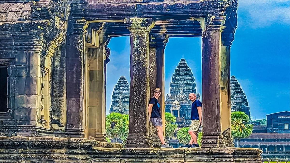 two people standing in a building with a painting of temples