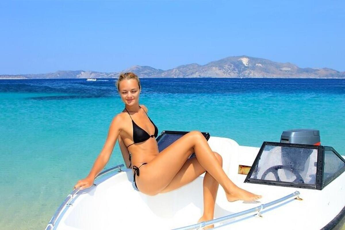 kona í bikiní sitjandi fremst á báti