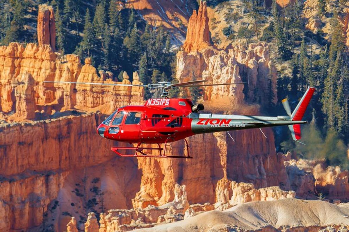 ein roter Hubschrauber fliegt über einen Canyon
