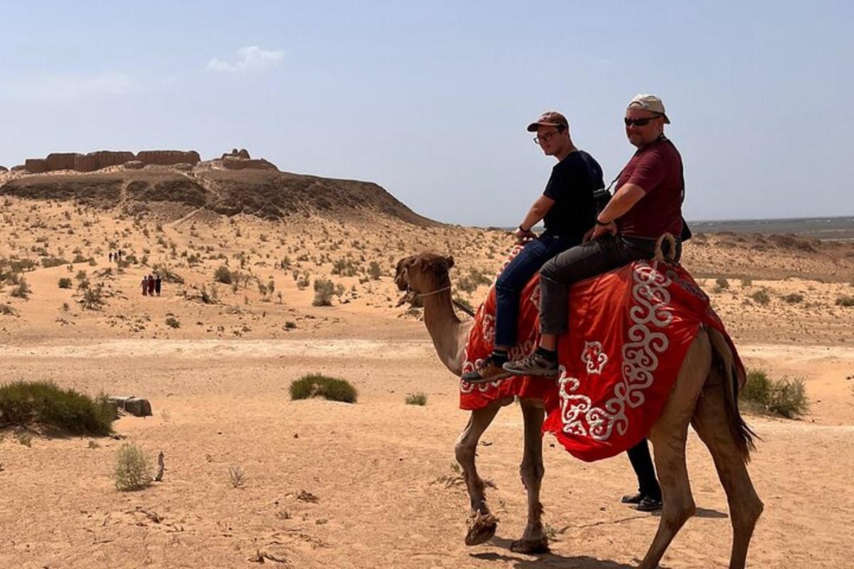 two people riding a camel in the desert