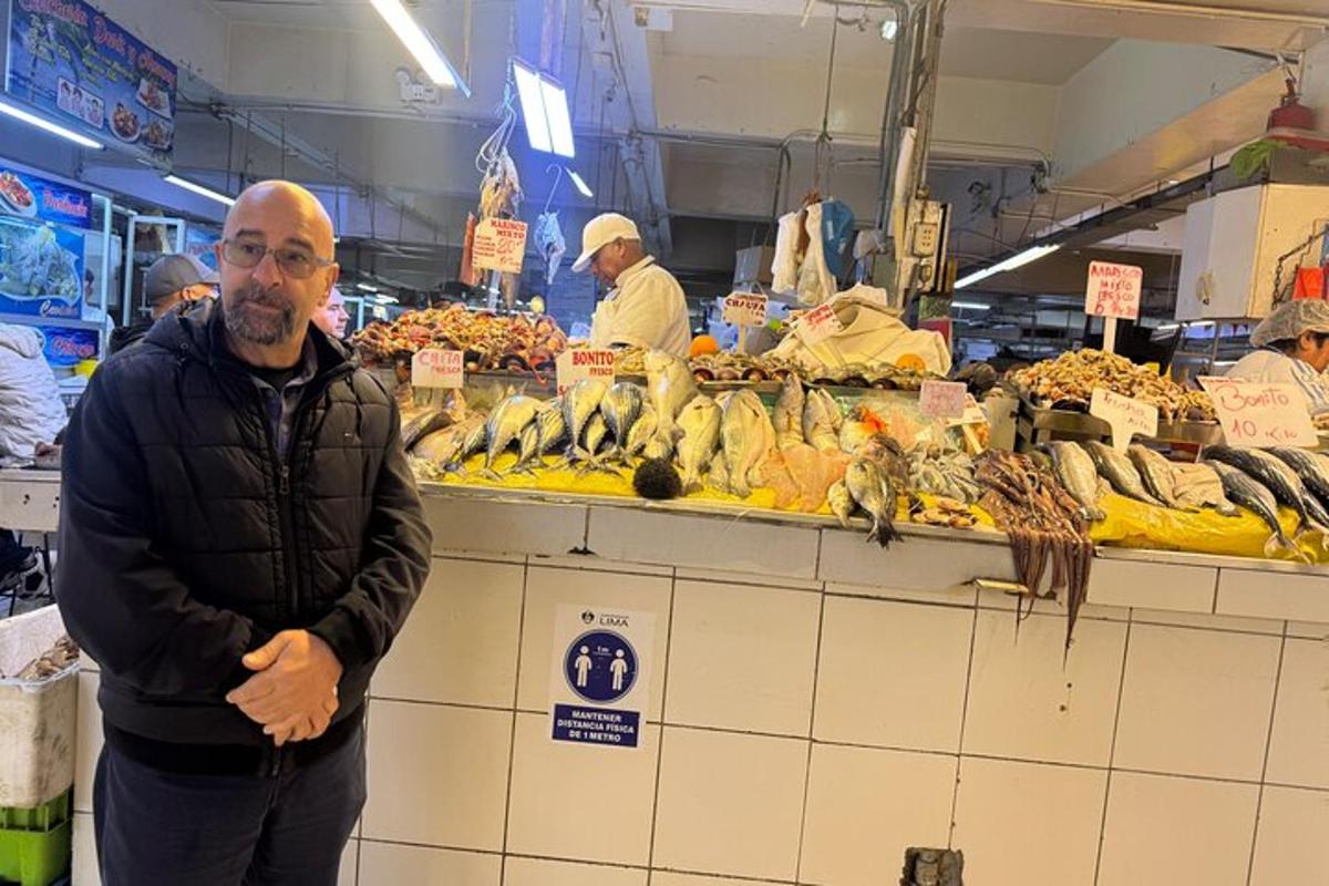 Egy férfi áll egy élelmiszerboltban egy csomó gyümölccsel
