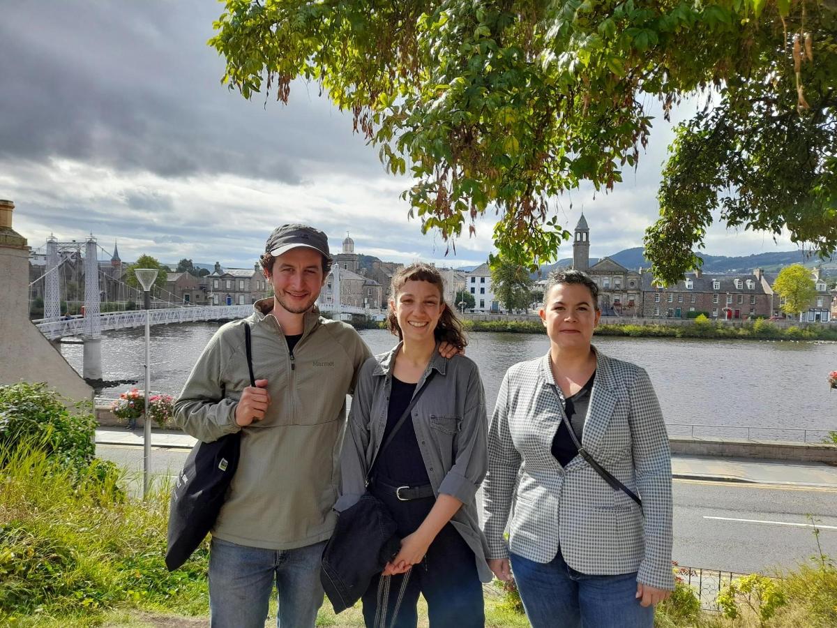 a man and two women standing next to a river