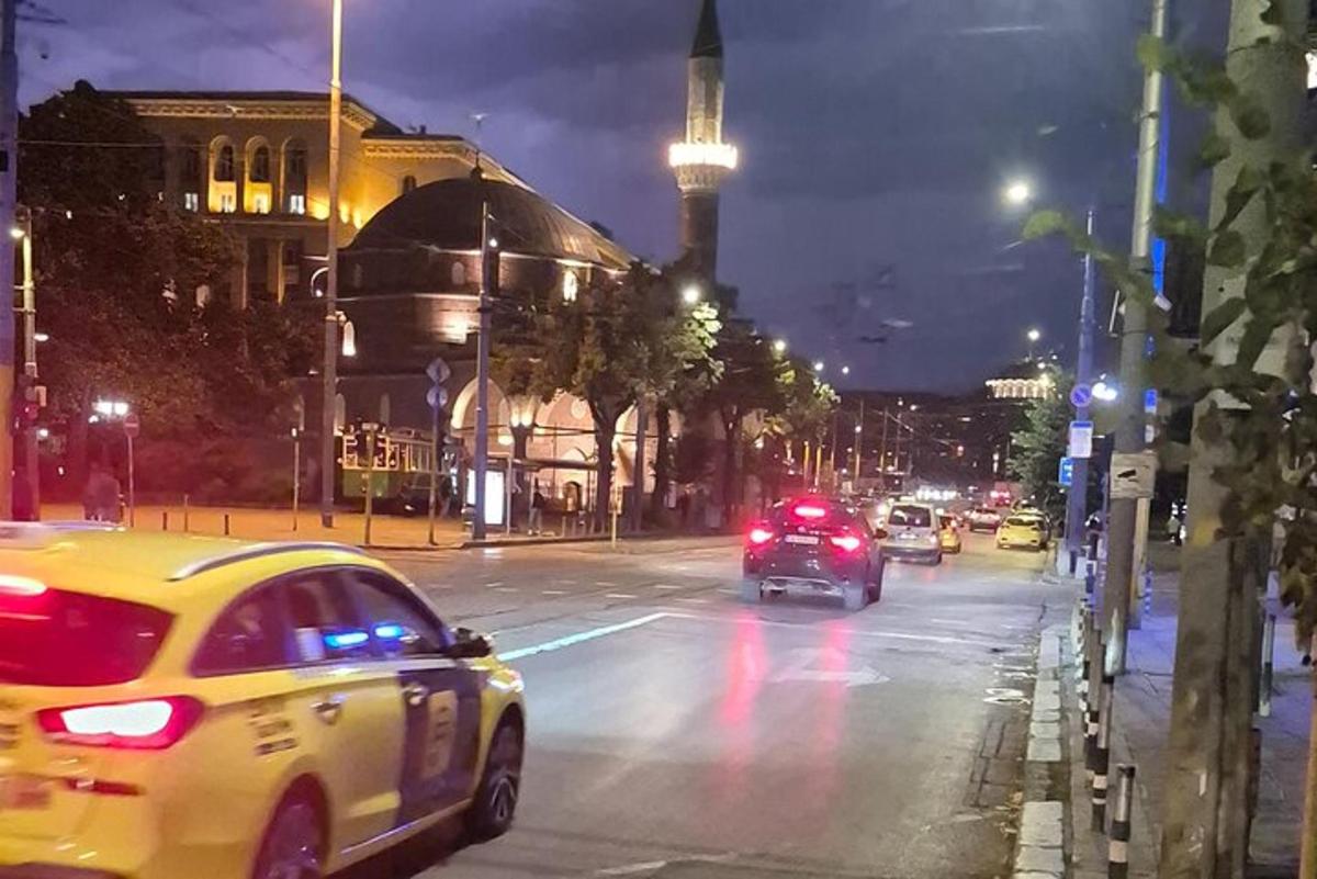 una strada cittadina di notte con le auto che la percorrono