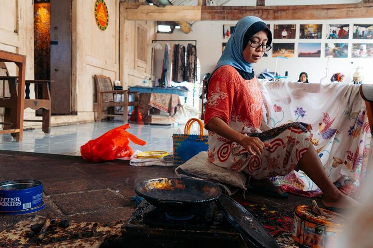 a woman sitting on the floor cooking food on a stove