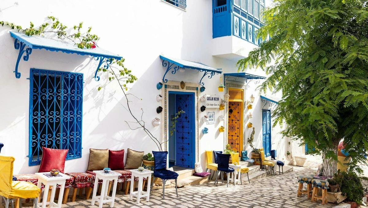 a building with blue doors and chairs on a street
