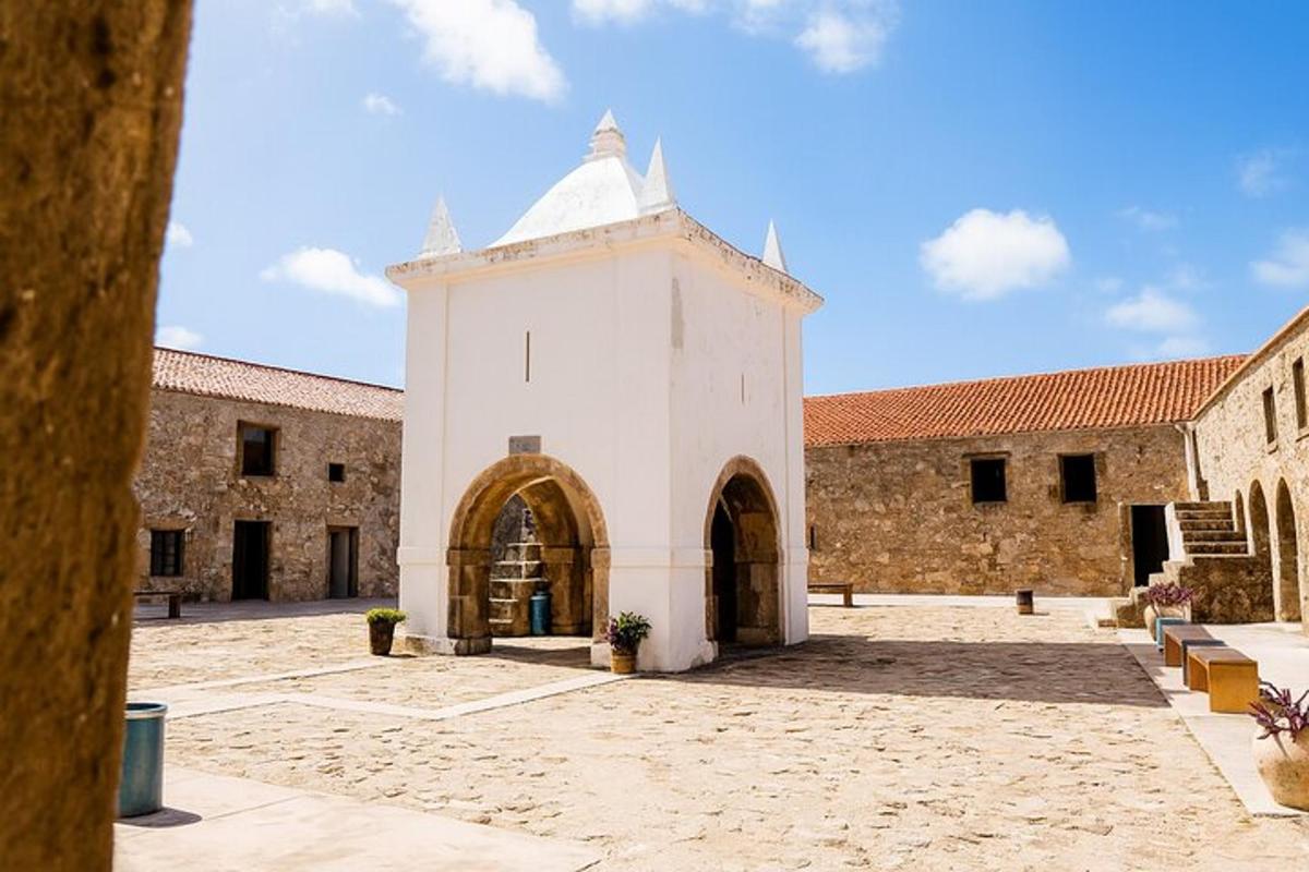 Un edificio blanco con una torre de reloj en un patio.