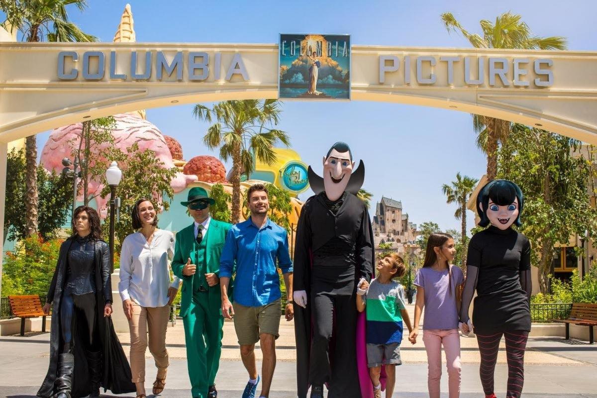 a group of people walking under the entrance to disneyland