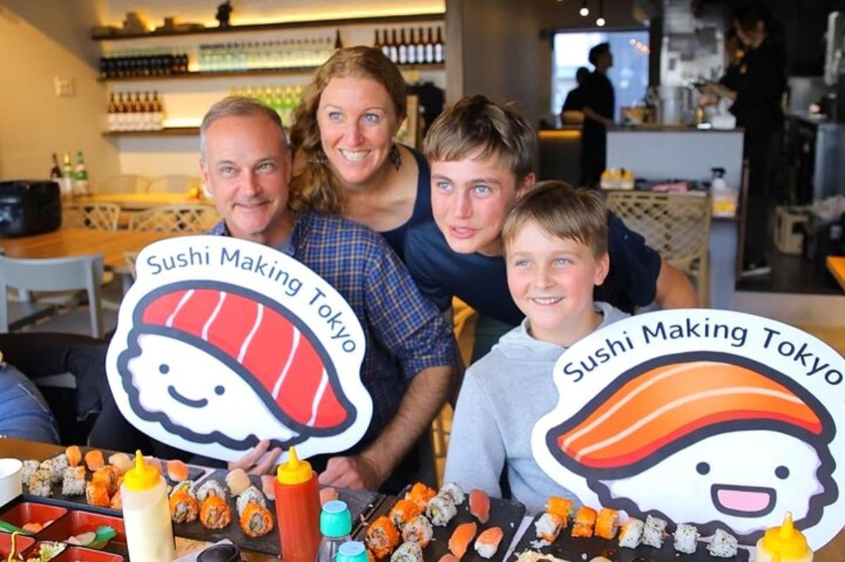 a family posing for a picture in front of sushi making tables