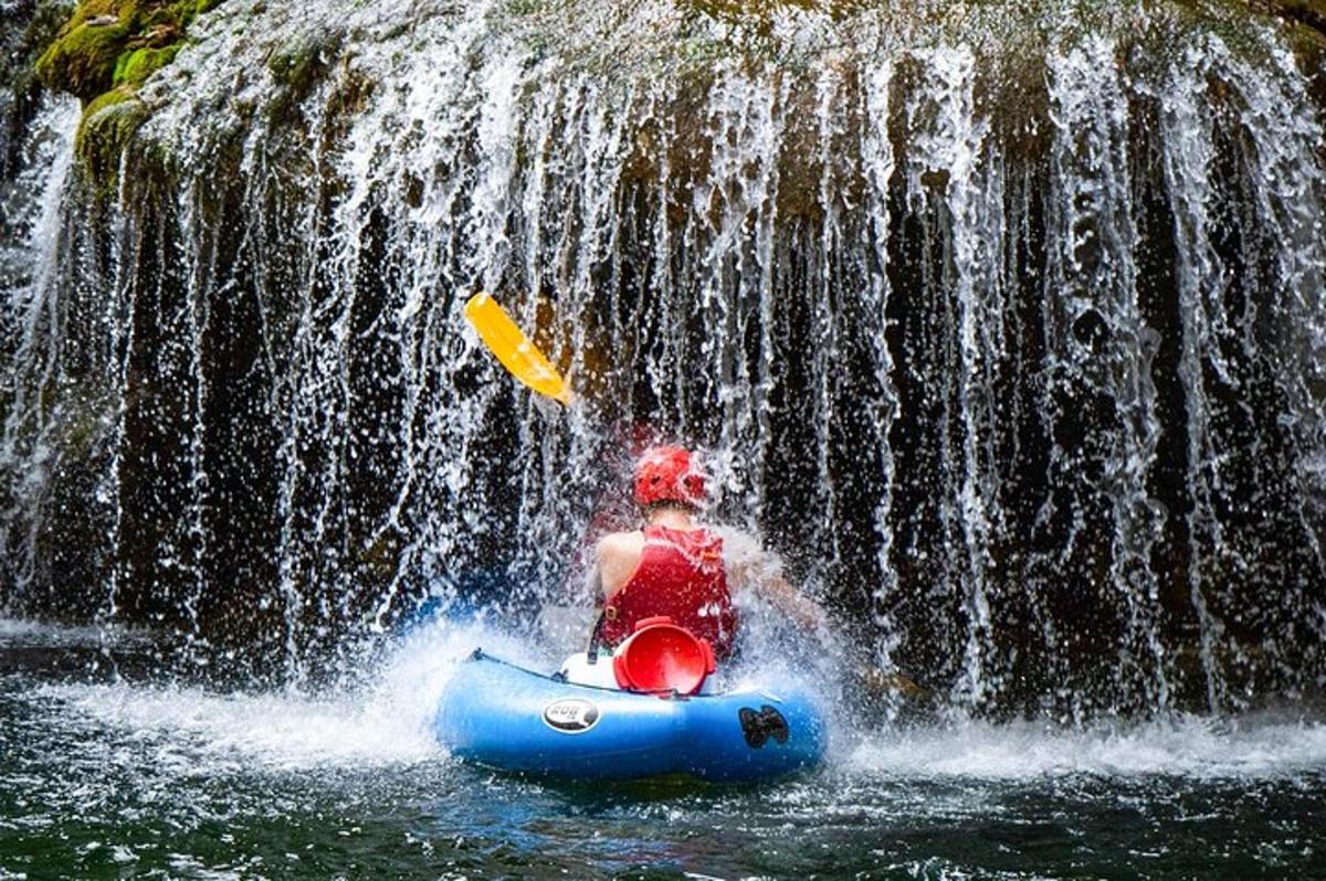 a man in a raft in front of a waterfall