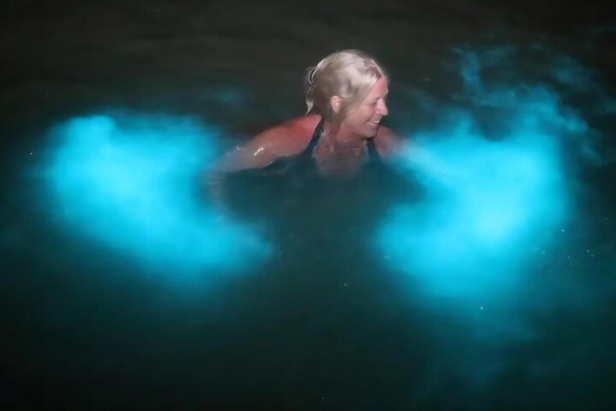 uma mulher nadando em uma piscina com luzes azuis
