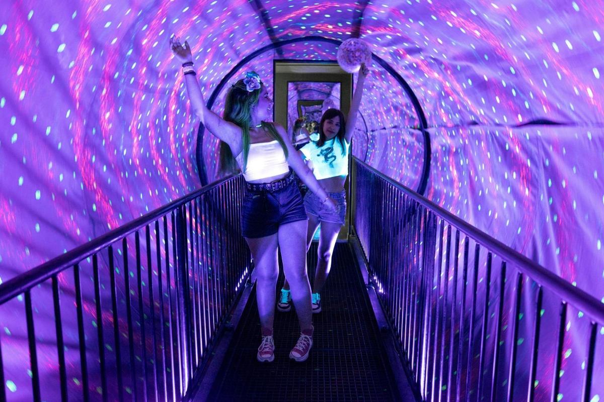 a woman walking down a tunnel with her arms in the air