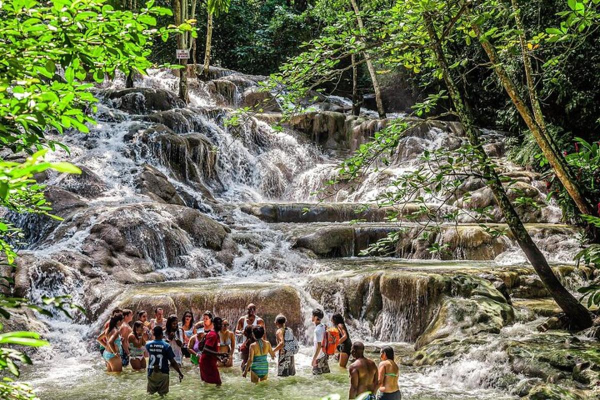 a group of people standing in the water near a waterfall