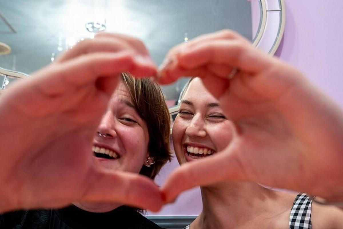 a woman is making a heart gesture in front of a mirror