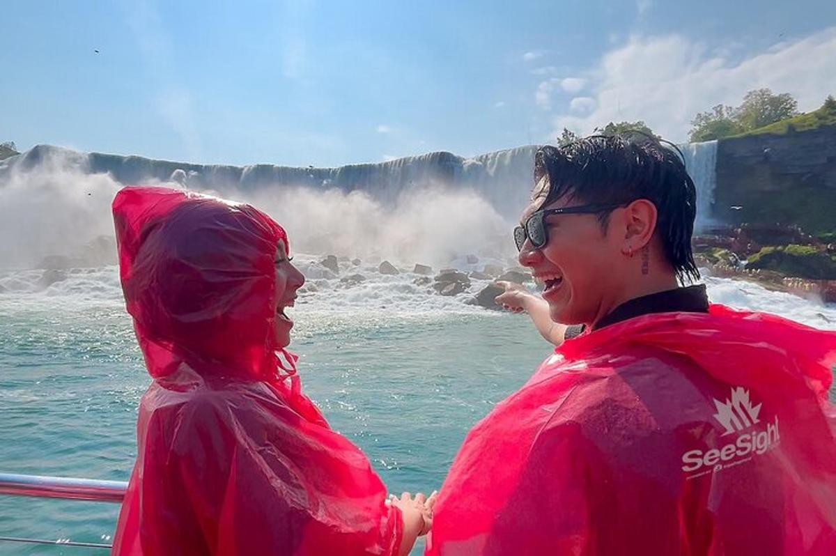 two people in red jackets standing in front of a waterfall