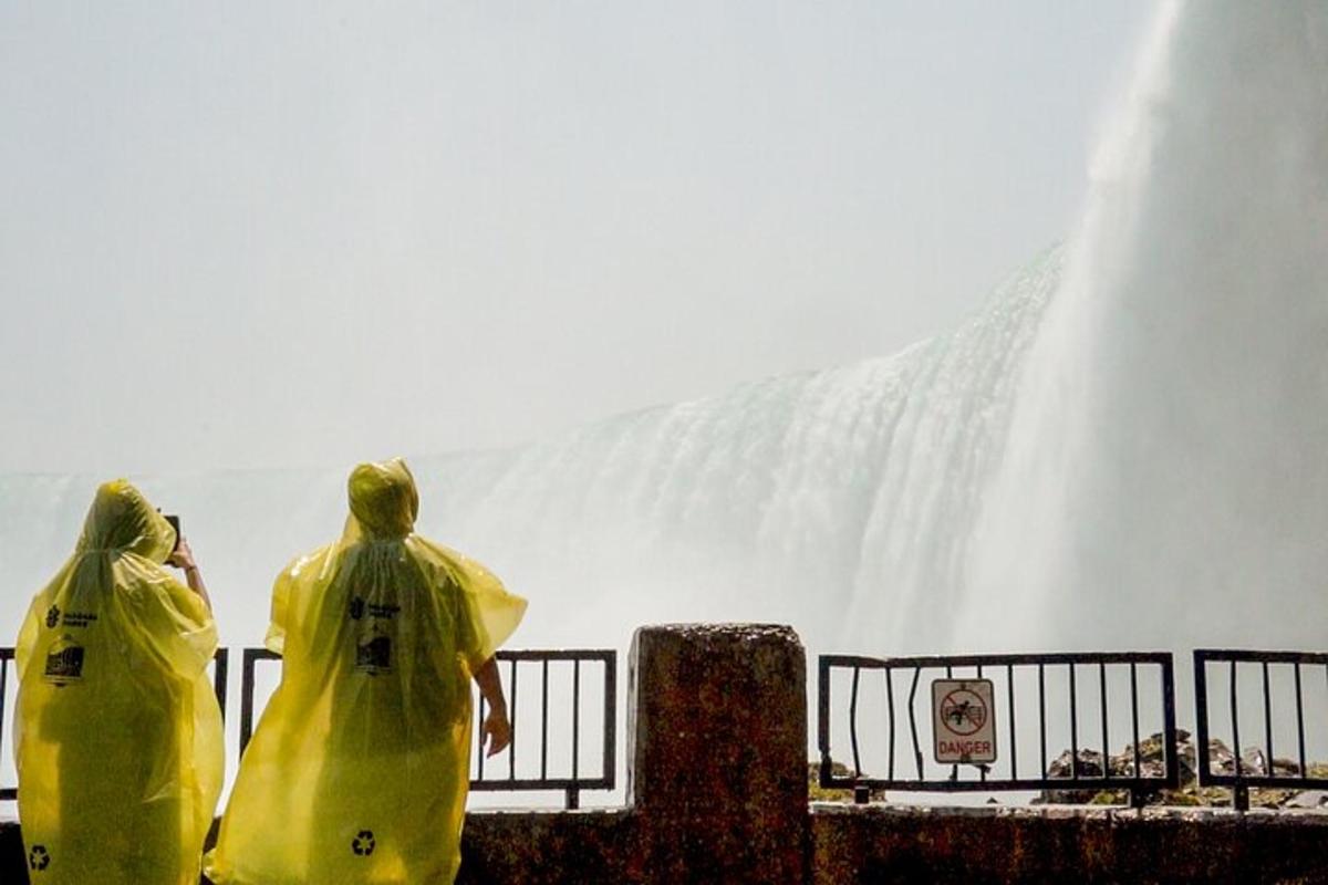 two people in rain coats standing in front of a waterfall
