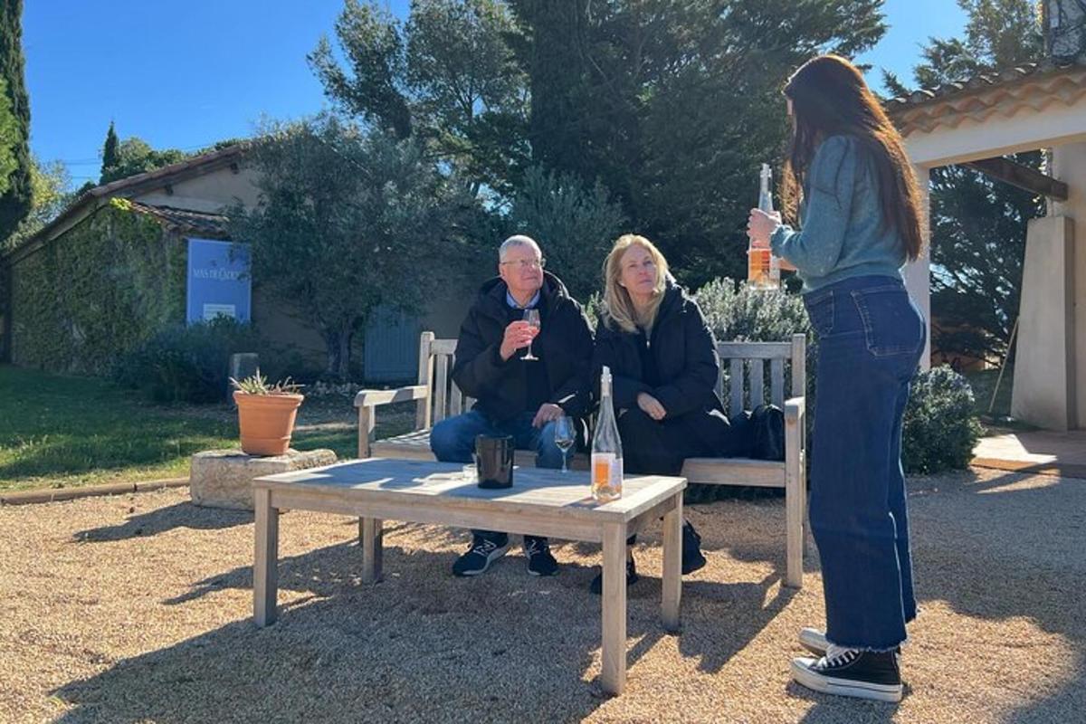 a woman holding a bottle of wine and a man sitting on a bench