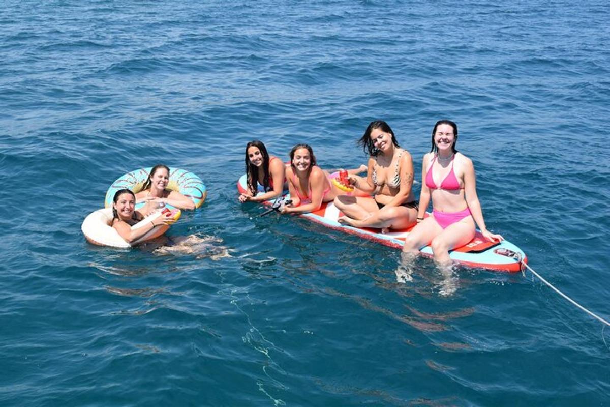un gruppo di donne sedute su una tavola da surf in acqua