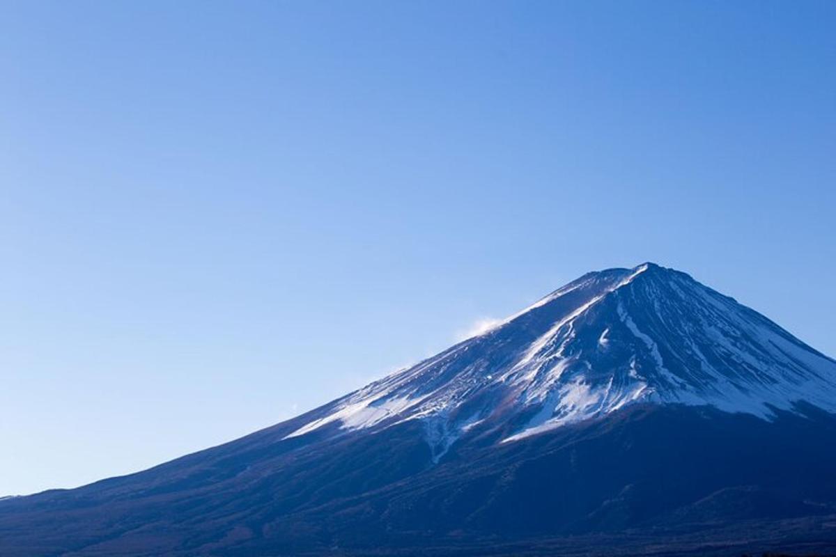 una muntanya nevada amb un cel blau al fons