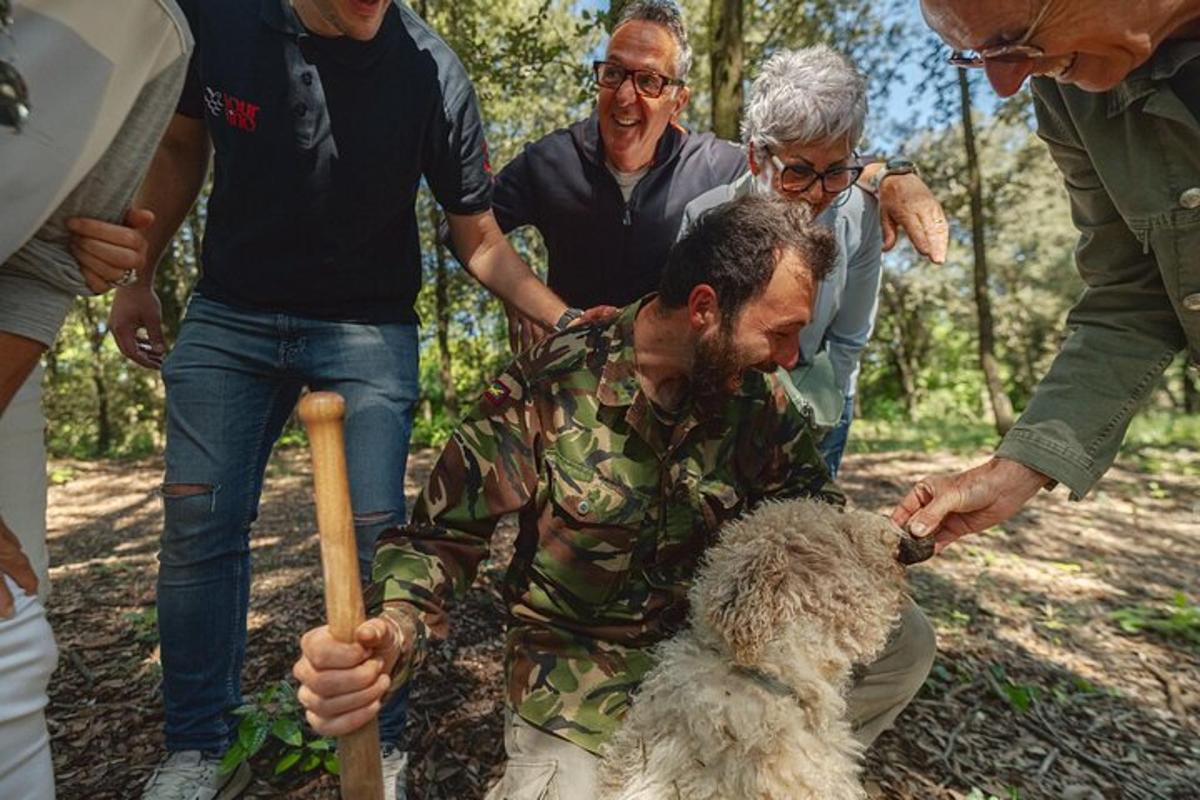 bir grup insanın arasında bir köpeği okşayan bir adam