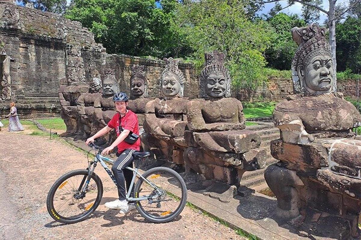 un bărbat pe bicicletă în fața unor statui