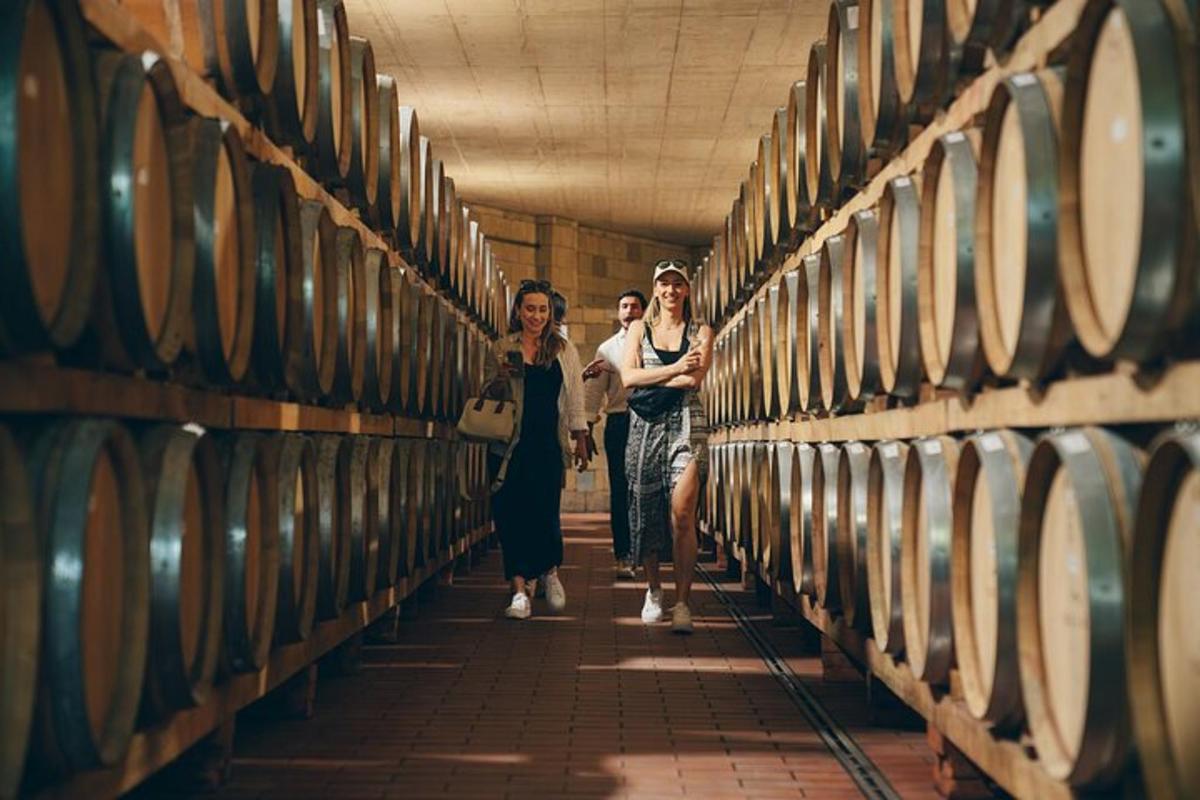 three women walking through a row of wine barrels