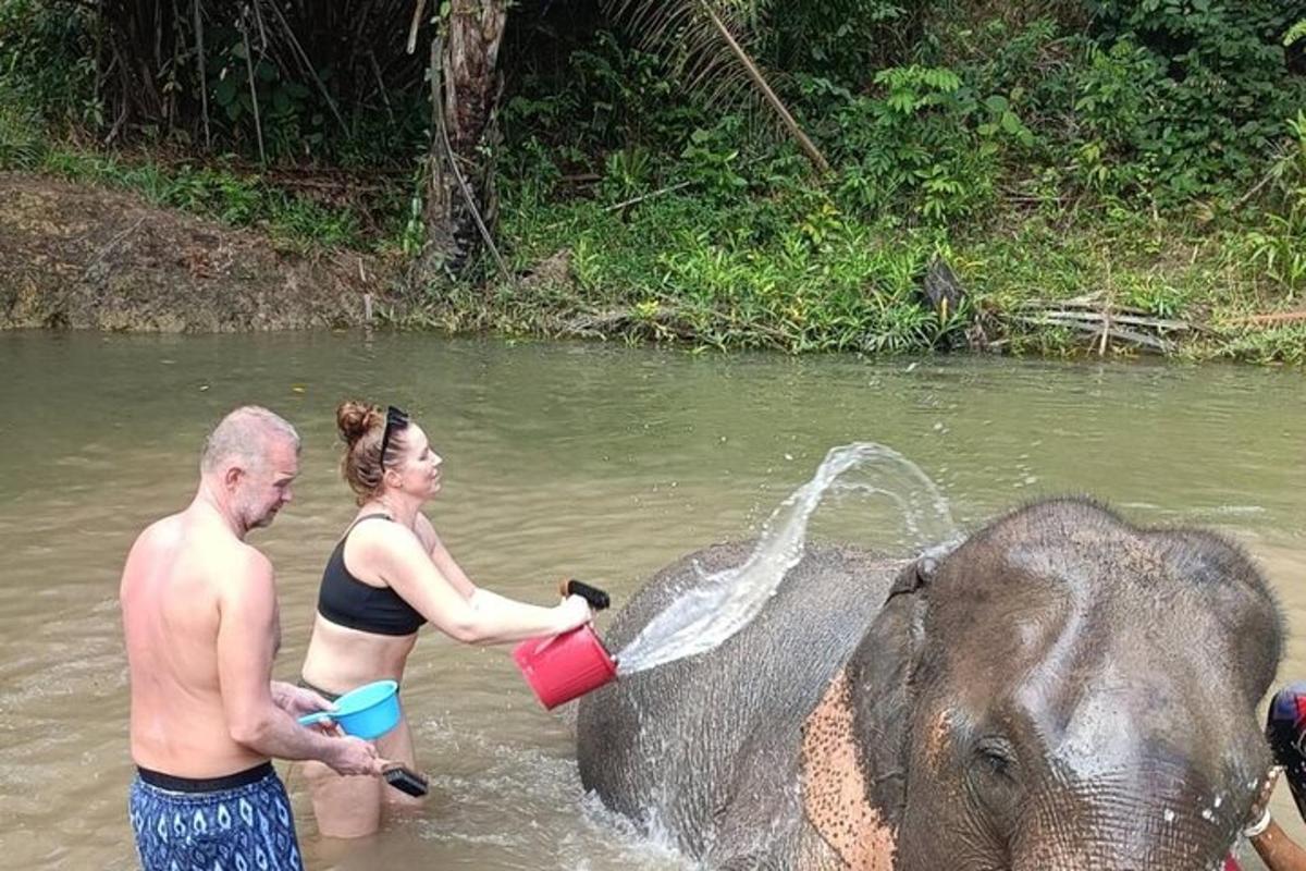 a man and a woman washing an elephant in the water