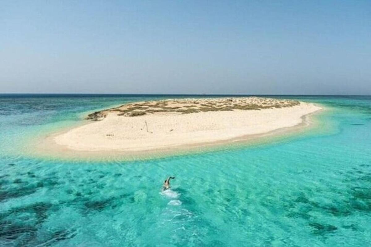 eine Person, die im Meer neben einer kleinen Insel schwimmt