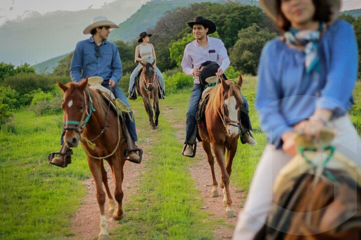 a group of people riding horses down a dirt road