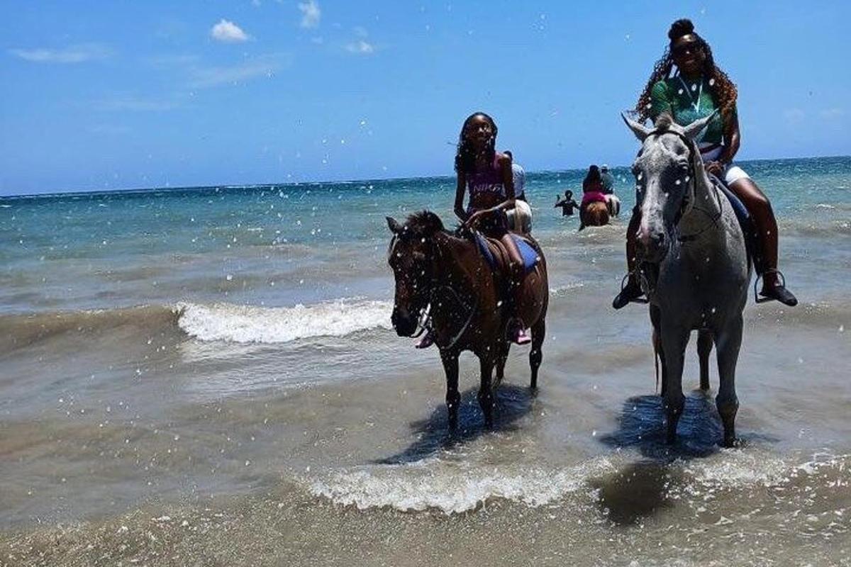dua orang sedang menunggang kuda di pantai