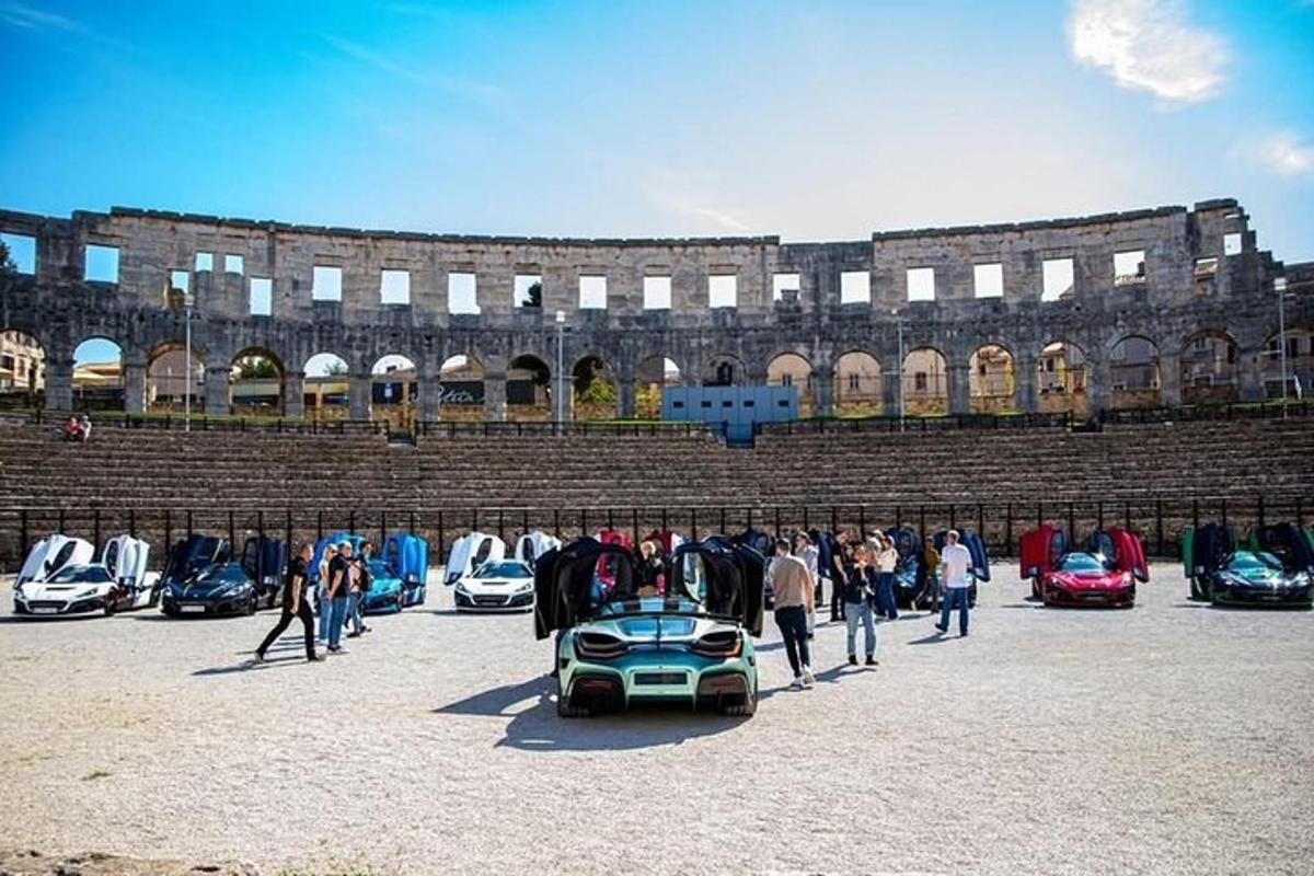 eine Gruppe von Menschen steht mit einem Auto auf einem Parkplatz