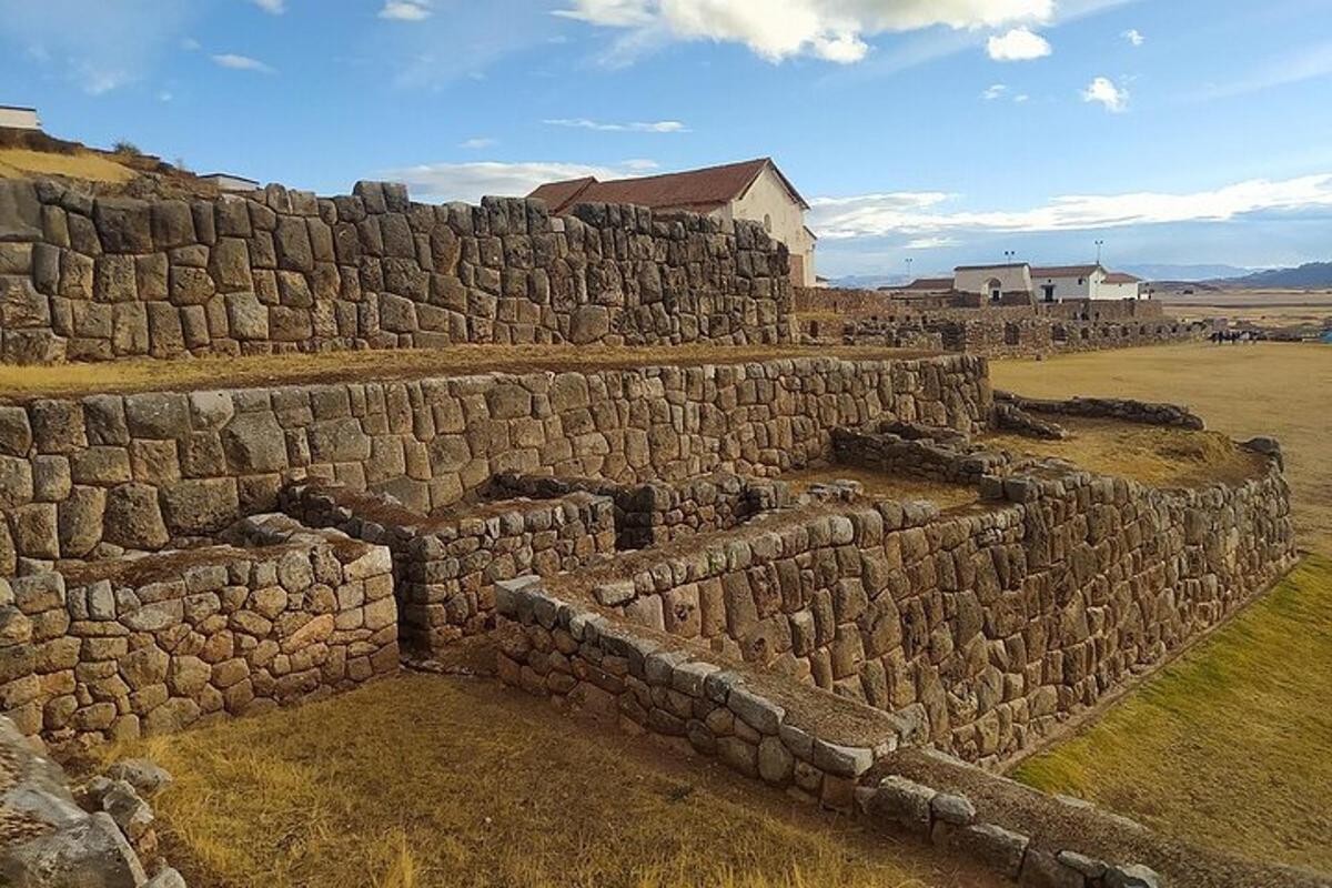 un vecchio muro di pietra in un campo con un edificio