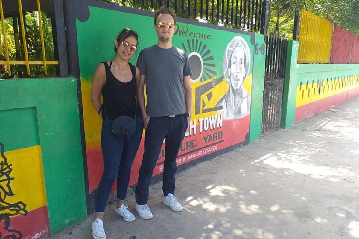 a man and a woman standing in front of a fence