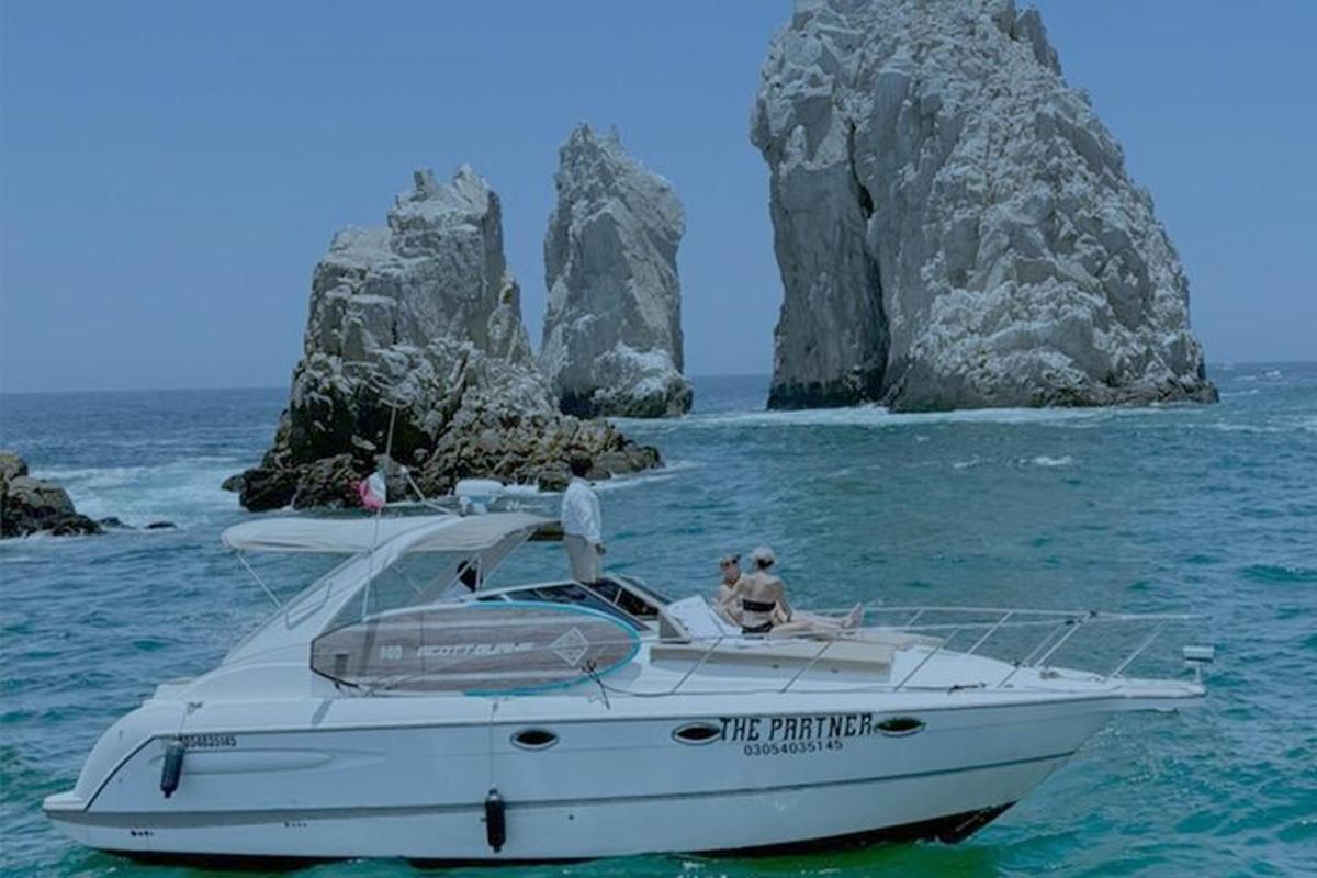two people sitting on a boat in the water with rocks