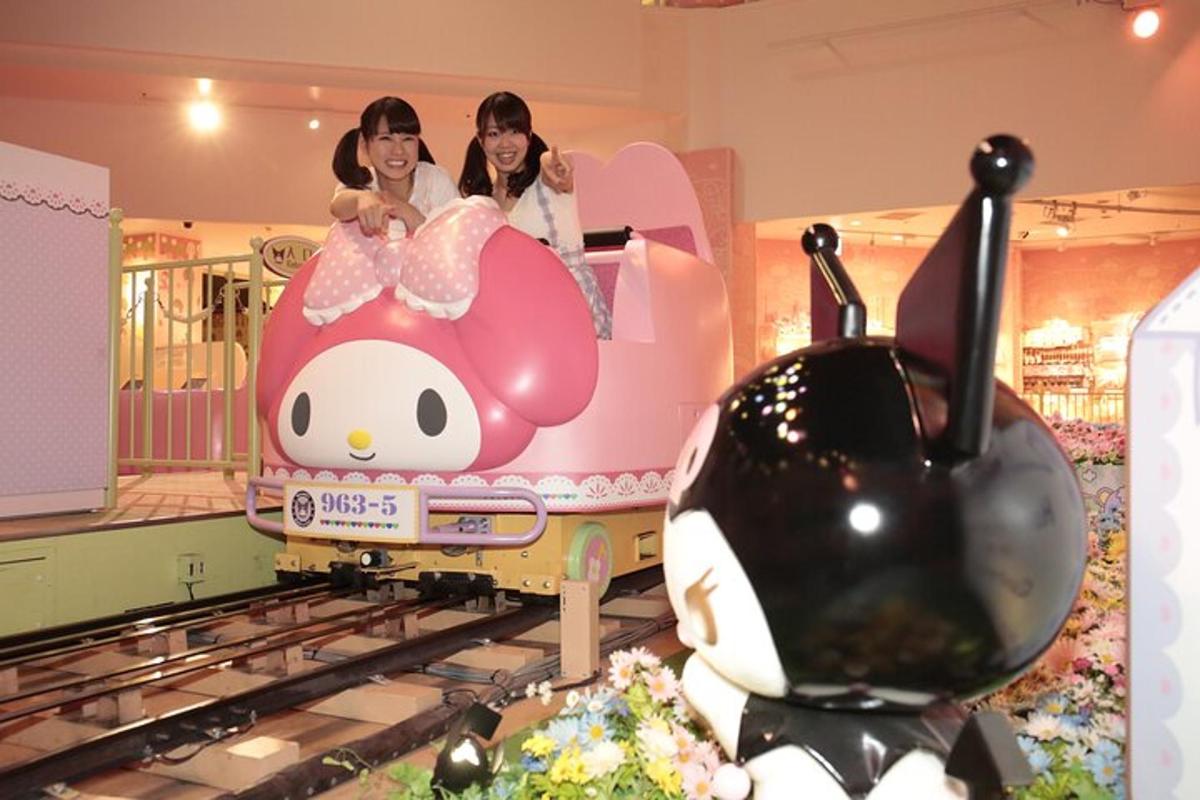 two girls riding on a toy train in a mall