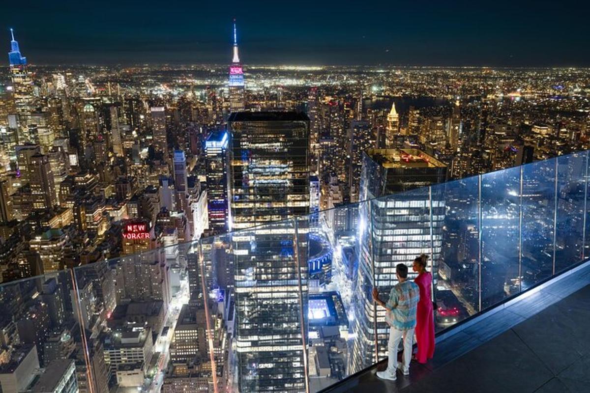 two people standing on top of a skyscraper at night