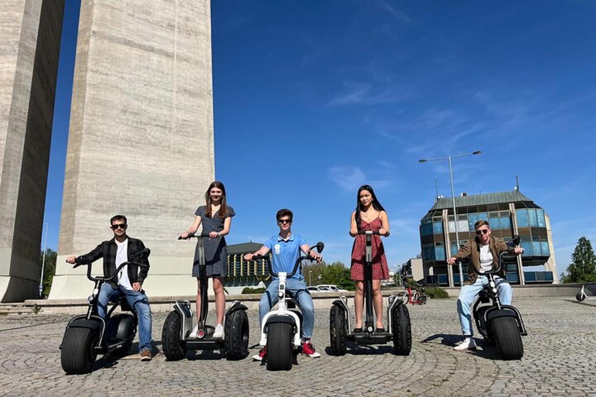 egy csoport ember segwayeken halad egy emlékmű előtt