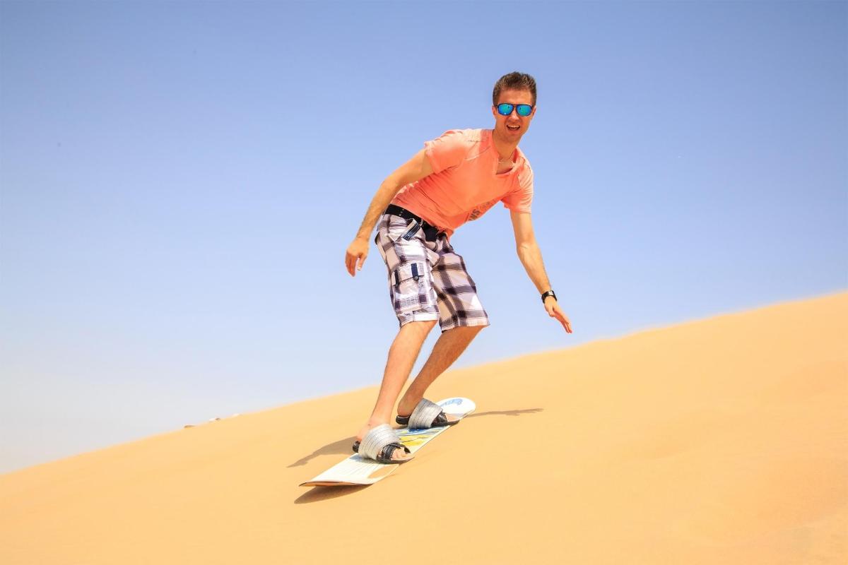 um homem andando de skate em uma duna de areia