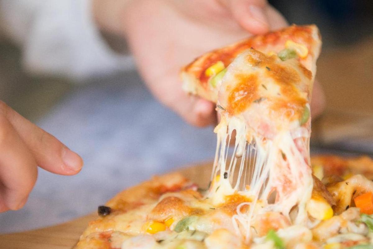 una persona comiendo una rebanada de pizza con un tenedor