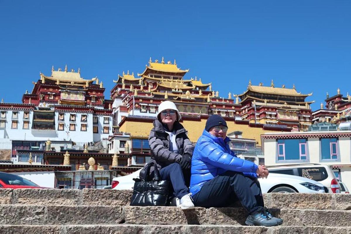 two people sitting on the stairs in front of buildings