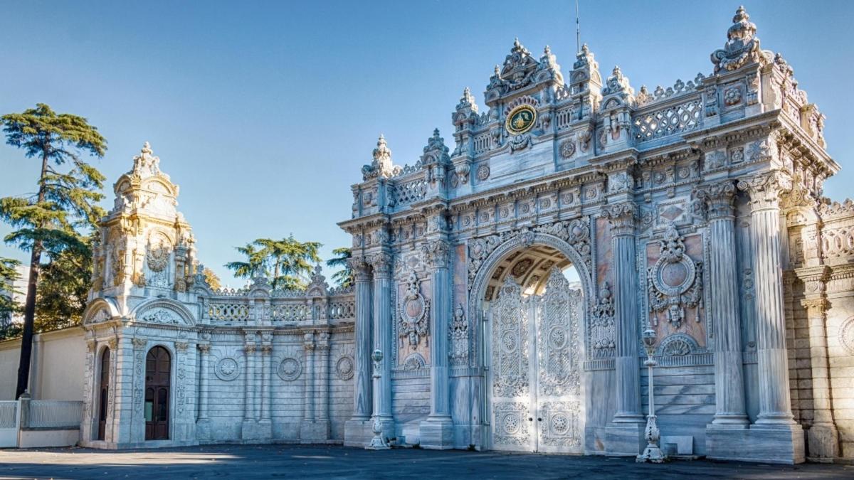 an ornate white building with a gate and palm trees