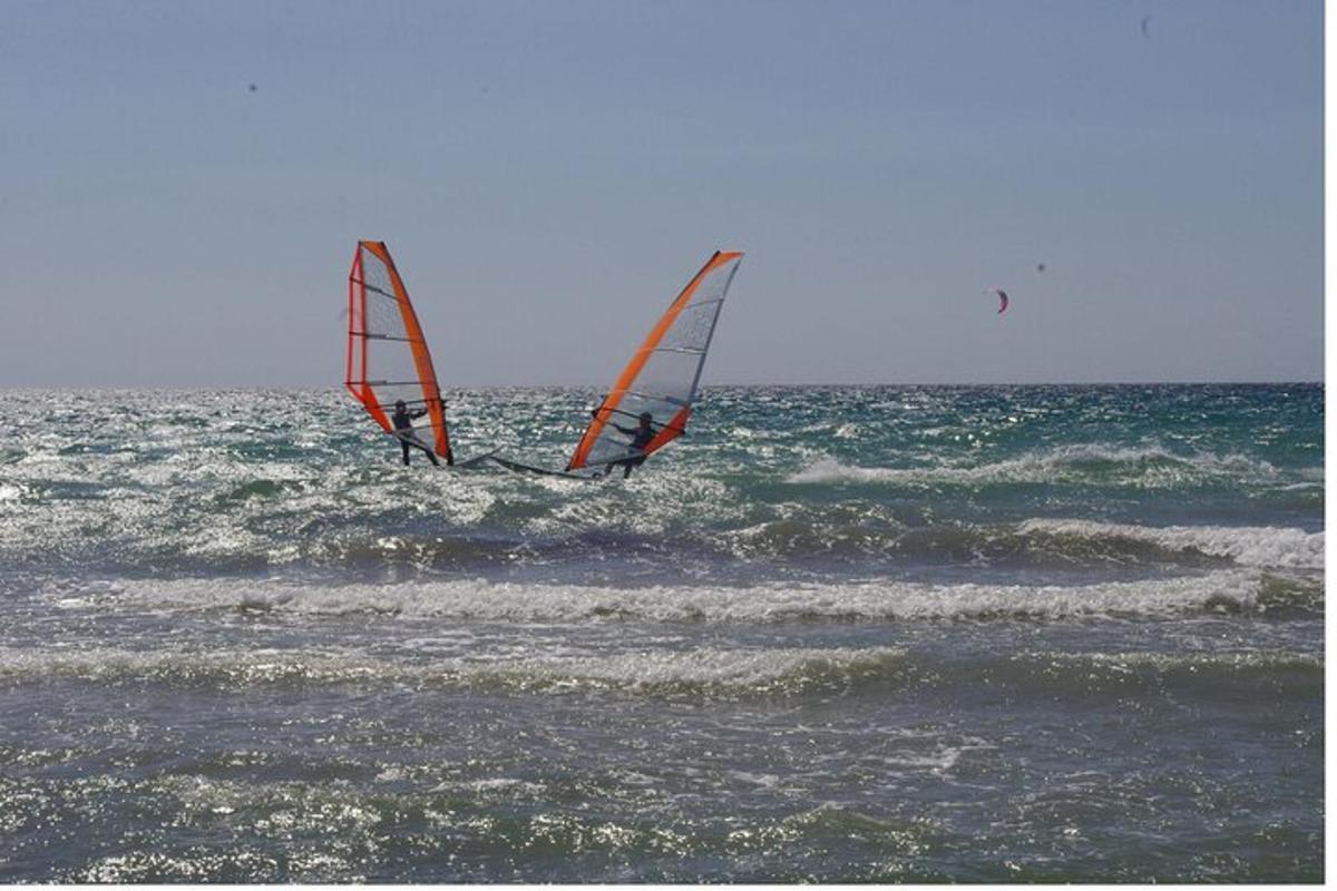 two people windsurfing in the ocean on the water