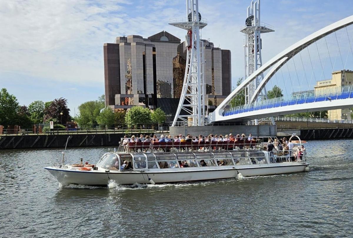 a boat full of people on the water near a bridge