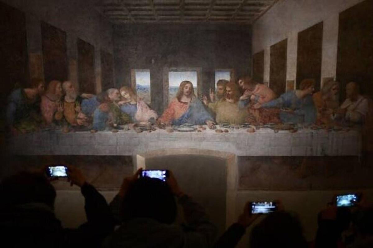 Un grupo de personas tomando fotografías de una pintura en una pared.