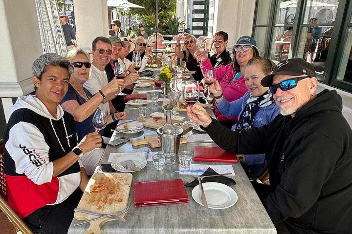 um grupo de pessoas sentadas em uma longa mesa com taças de vinho