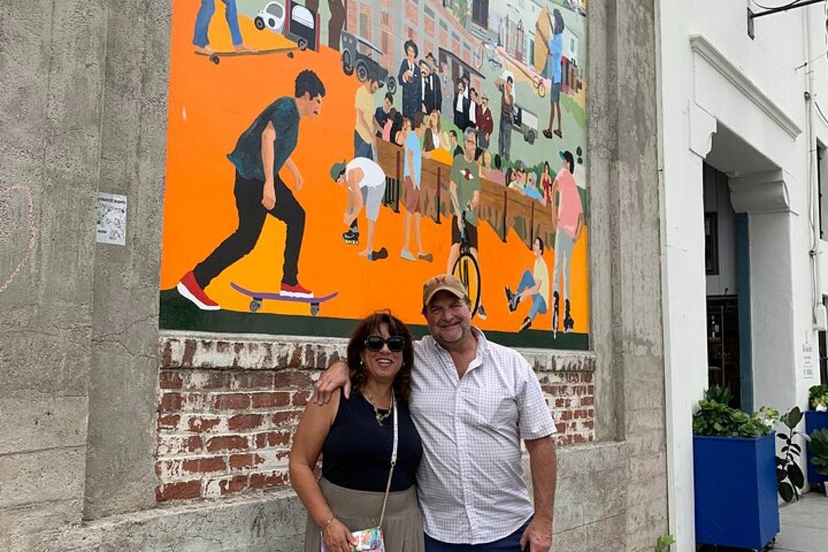 um homem e uma mulher em pé em frente a um mural