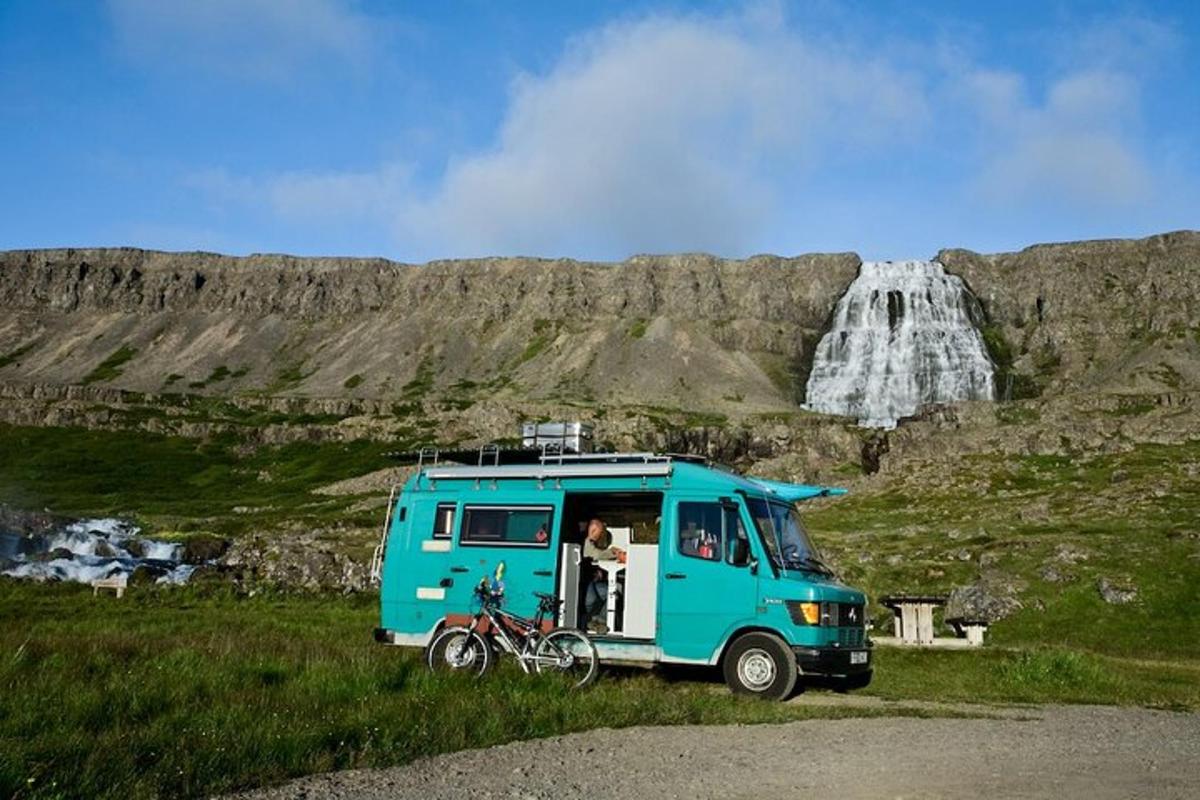 a blue truck parked in a field next to a waterfall