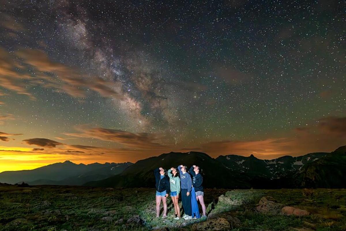 a group of people standing on a hill under the stars