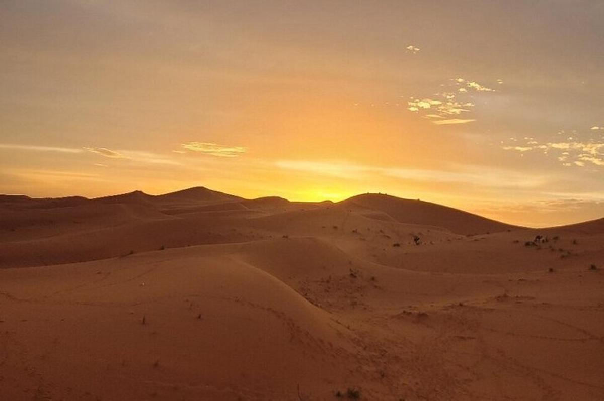 un tramonto nel deserto con colline e sabbia