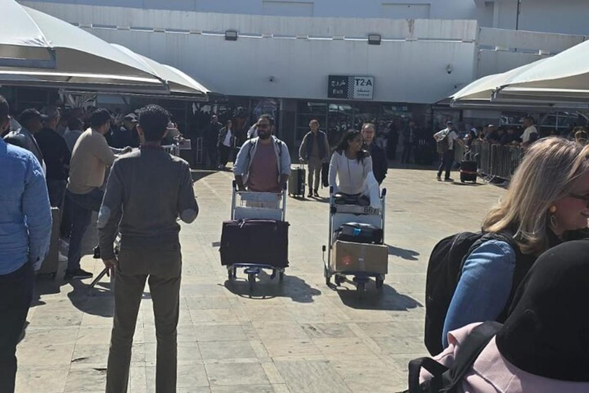 un gruppo di persone che camminano in un aeroporto con i bagagli